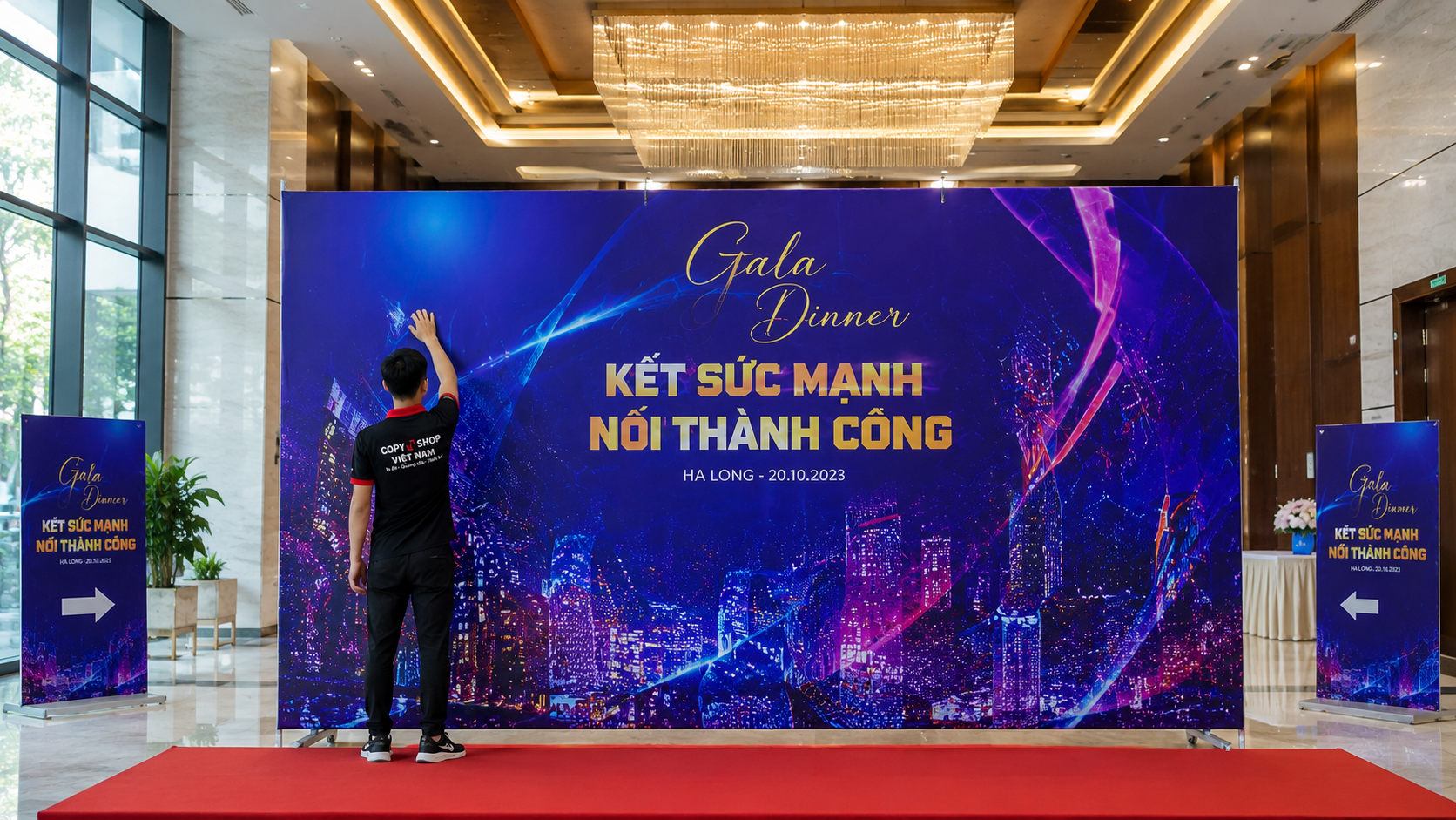 bảng giá in bạt quảng cáo 6 Nhân viên lắp đặt backdrop hoàn thiện tại khu vực trung tâm hội nghị